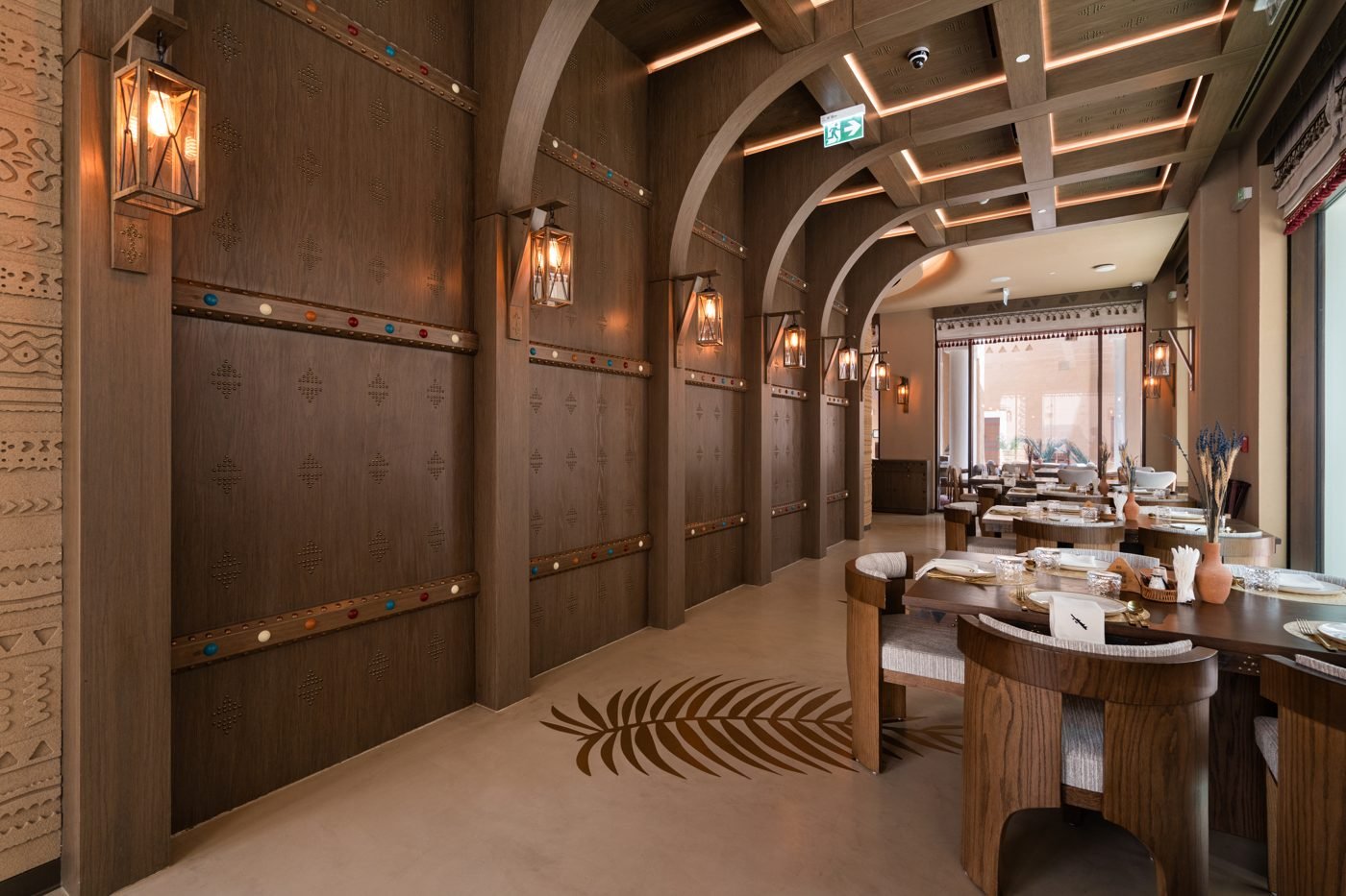 The dining room at Aseeb Restaurant, Diriyah: timber arches, lanterns and a carved gypsum wall