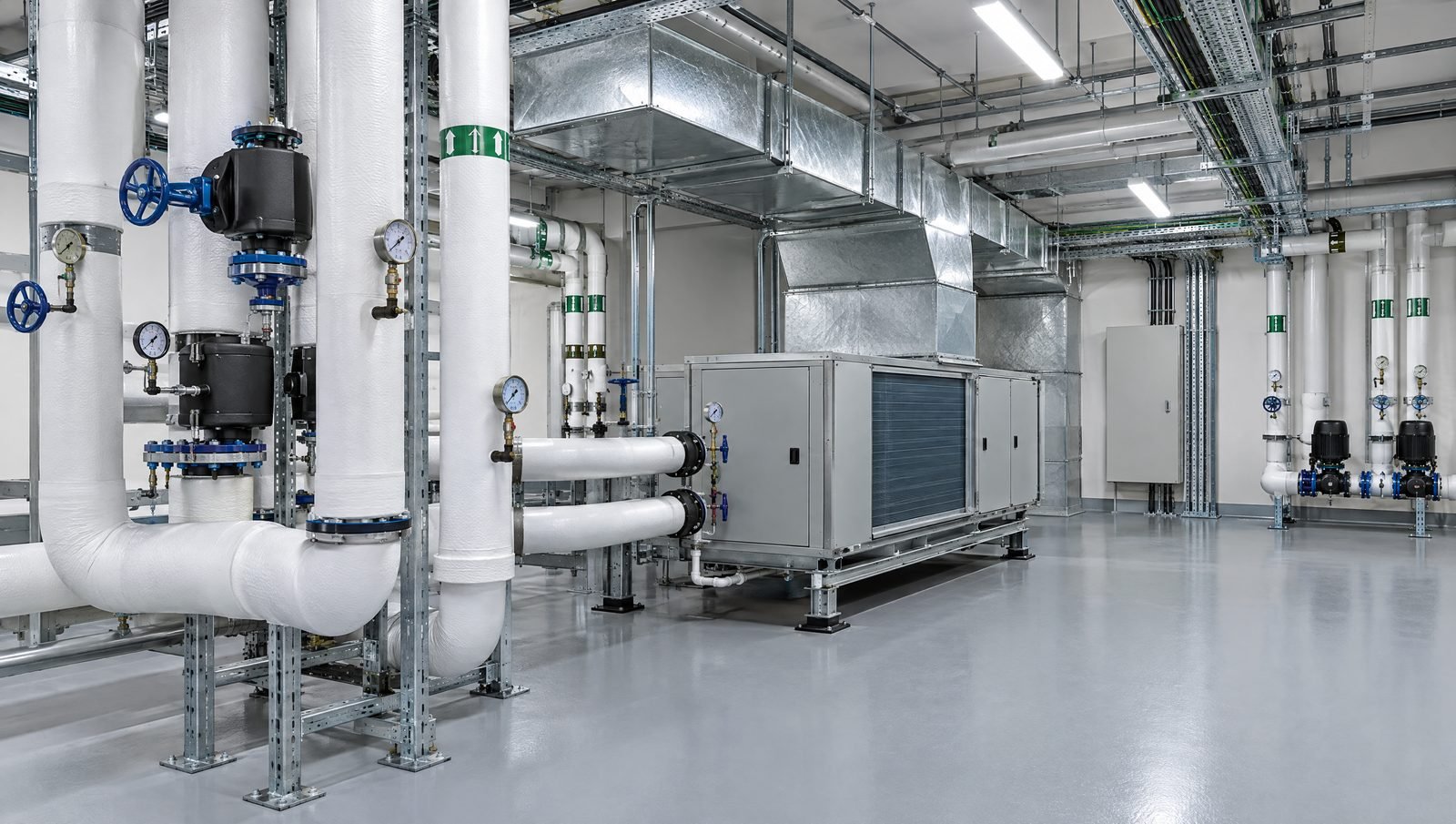 A commercial HVAC plant room with insulated pipework, valves, a fan coil unit and ductwork