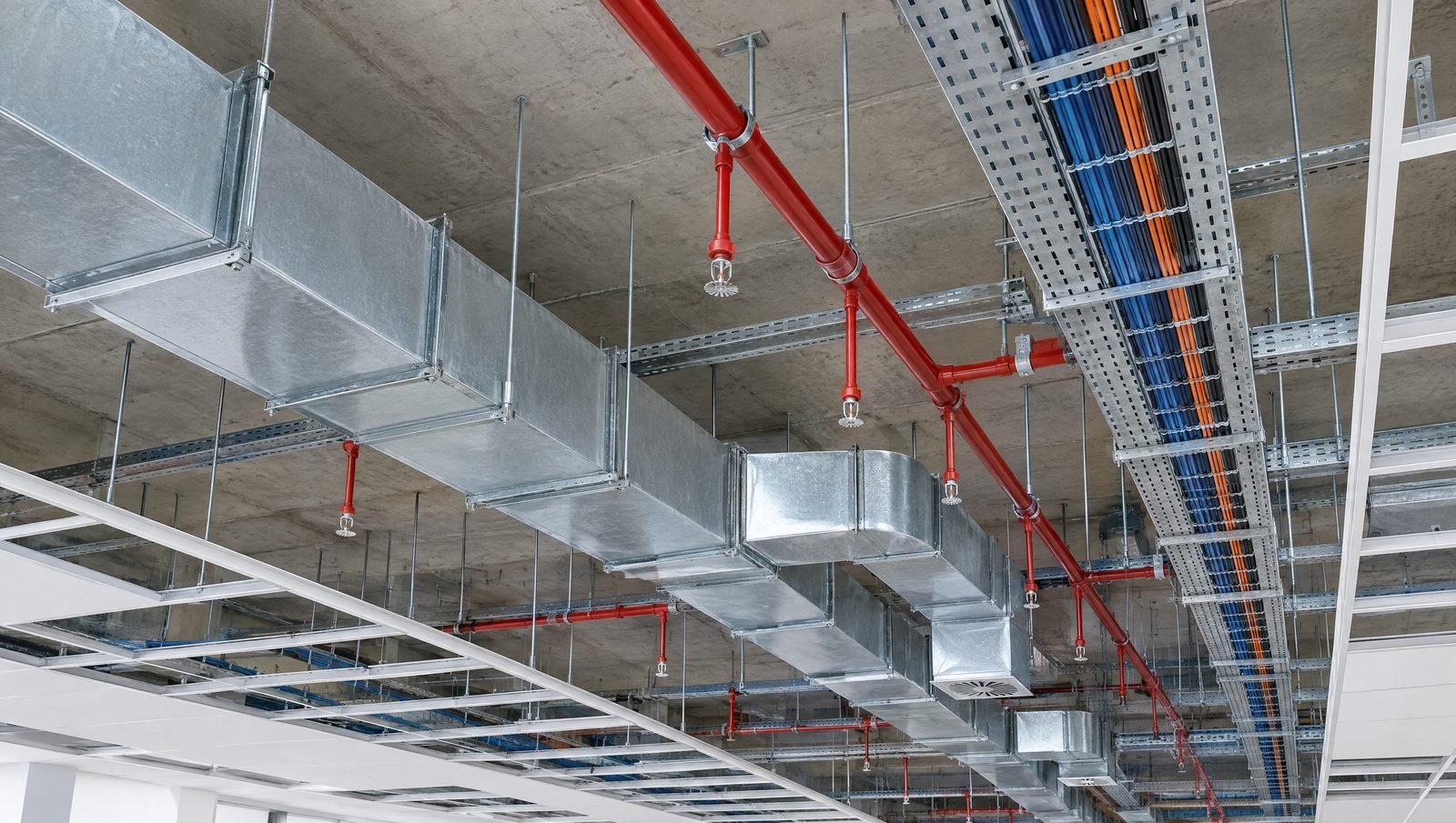 Ductwork, cable trays and red sprinkler mains installed neatly above an open ceiling